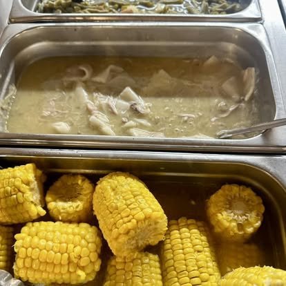 Steam table with corn on the cob, chicken and pastry, and collard greens